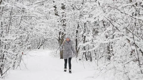 Girl in the winter forest during a snowfall blows a kiss. She's happy. Stock Footage 130877210