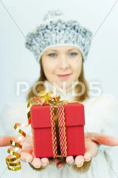 Girl in winter hat gives gift box Stock Photos