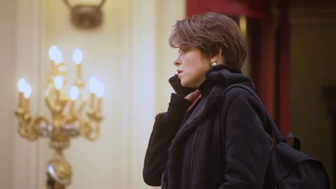 Girl in winter jacket with backpack seriously talking on the phone, profile, int Vidéo 114222596