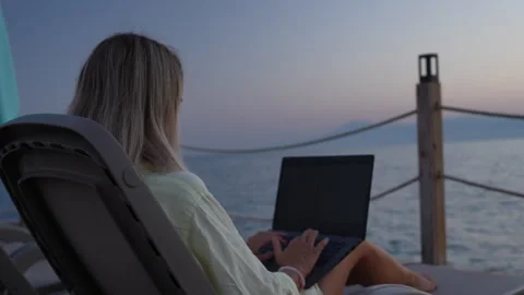 A girl is working on a computer at the beach. Stock Footage 282237272