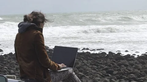 Girl working on computer in front of the ocean Video stock 80318373