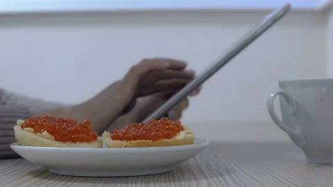 Girl working on computer in light room .Ofis. Eating a sandwich with caviar. Stock Footage 73063460