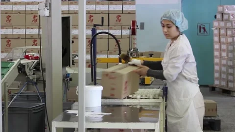 A girl working as a packer puts a label on a box of sweets Stock Footage 128643153