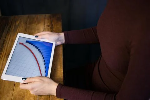 The girl working with a tablet computer. The graph rises. Table, wooden, back Stock Photos