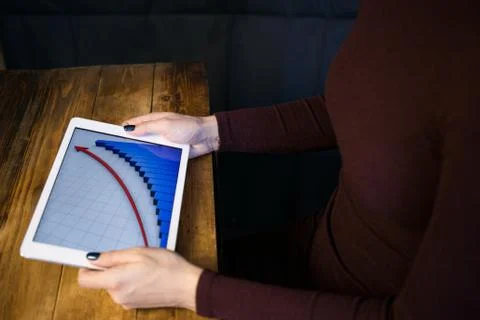 The girl working with a tablet computer. The graph rises. Table, wooden, back Stock Photos
