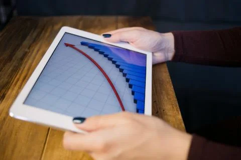 The girl working with a tablet computer. The graph rises. Table, wooden, back Stock Photos