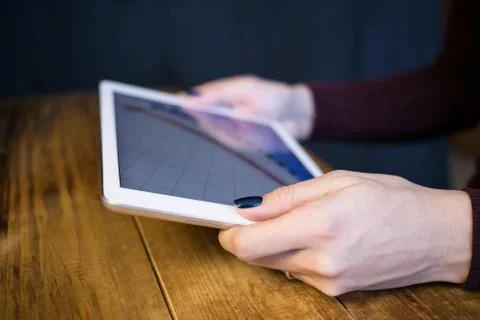 The girl working with a tablet computer. The graph rises. Table, wooden, back Stock Photos