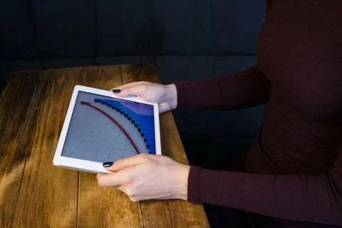 The girl working with a tablet computer. The graph rises. Table, wooden, back Stock Photos