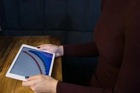 The girl working with a tablet computer. The graph rises. Table, wooden, back Stock Photos
