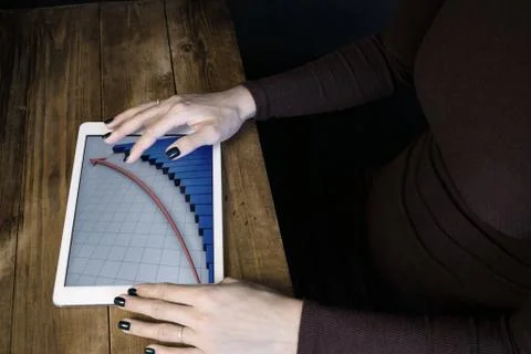 The girl working with a tablet computer. The graph rises. Table, wooden, back Stock Photos