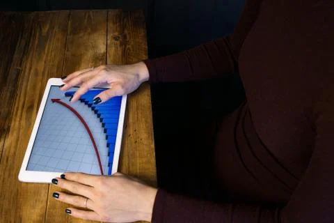The girl working with a tablet computer. The graph rises. Table, wooden, back Stock Photos