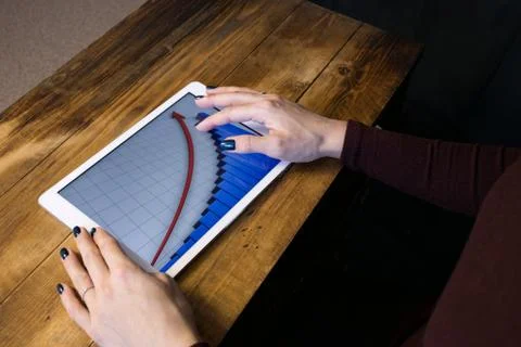 The girl working with a tablet computer. The graph rises. Table, wooden, back Stock Photos
