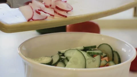 The girl works in the kitchen, throws radish in a bowl. Vídeo Stock 106930607