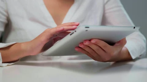 The girl works at the tablet, leafs through the file with her hand. Close-up Stock Footage