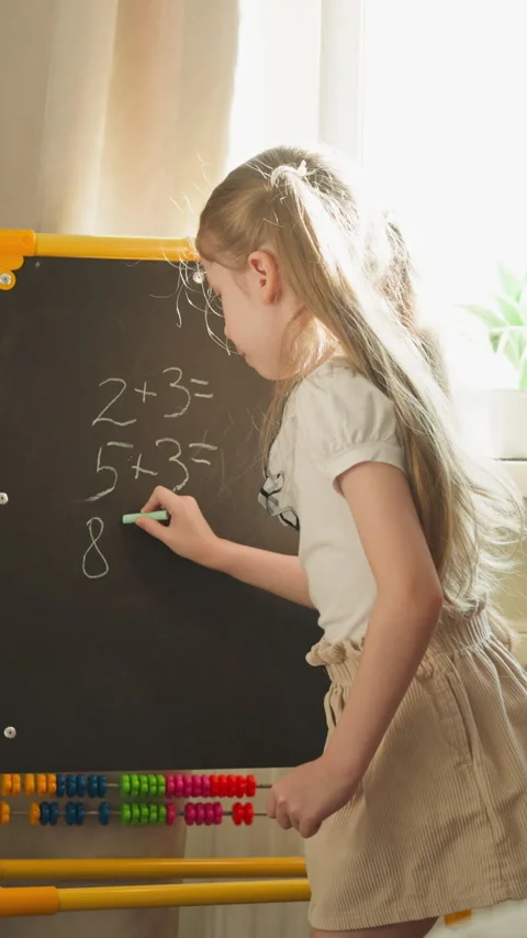 Girl writes math problems for brother playing school at home Stock Footage 275078863