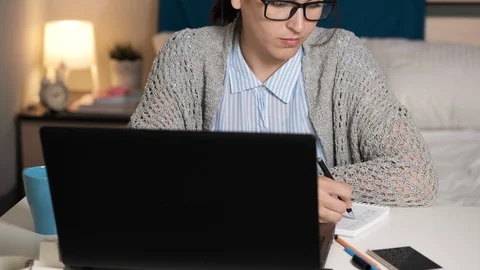 Girl writes in notebook drinking coffee or tea and works at computer. Woman Video stock 129087654