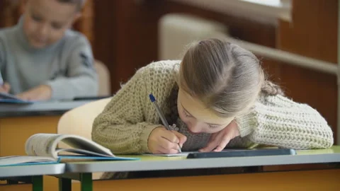 The girl writes while sitting at her desk Stock Footage 100535903