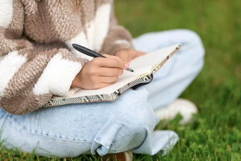 Girl writing notes with pen while sitting in the street. Foto stock