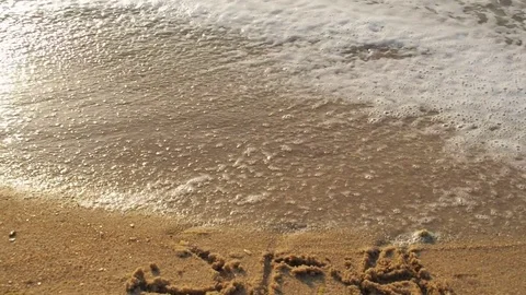 The girl is writing on the wet sand the inscription of the sea. Stock Footage