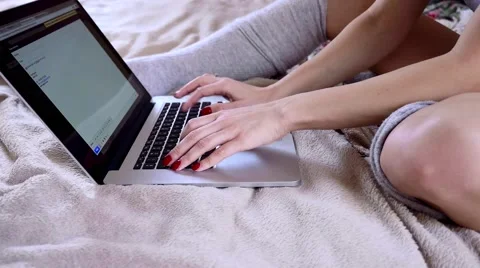 Girl writting e-mail on her laptop. She is sitting on the bed. Close up. Stock Footage 61137105