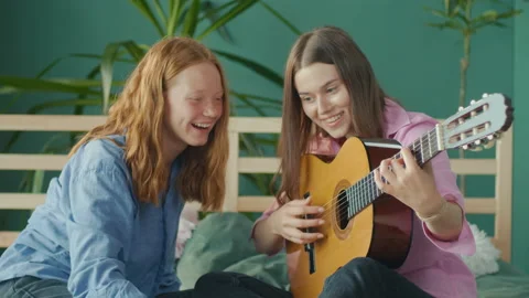 Girlfriend Teaches To Play Guitar While Sitting on the Bed at Home. Stock Footage 210887308