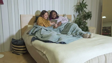 Girlfriends Are Lying In Bed Using A Tablet Are At Home, Evening, Smiling Stock Footage 139276037