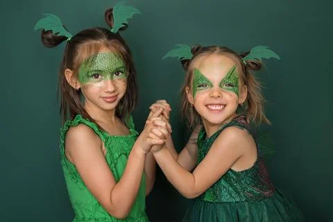Girlfriends dressed up as dragons with pattern on face are holding hands Stock Photos