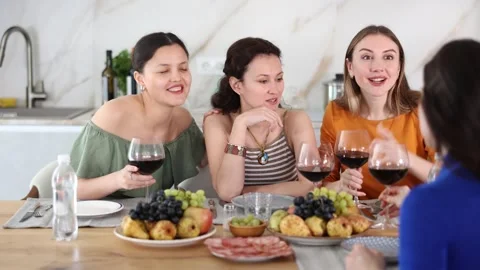 Girlfriends drinking wine and having conversation over dinner at a house party Stock Footage 312229546