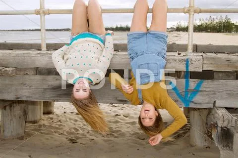 Girlfriends Hanging Upside Down From Pier