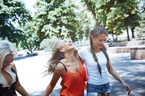Girlfriends having fun while walking on the sidewalks of downtown Stock Photos