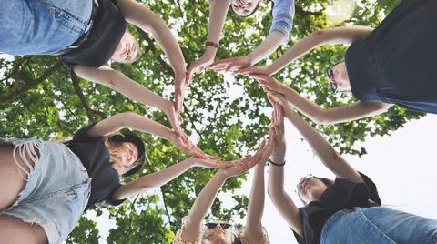 The girlfriends join their palms in a circle against the background of tree Stock Photos