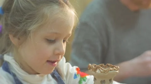 Girls And Man at Pottery Workshop Little Girl Smiling And Glazing Clay Figurine Stock Footage 59129641