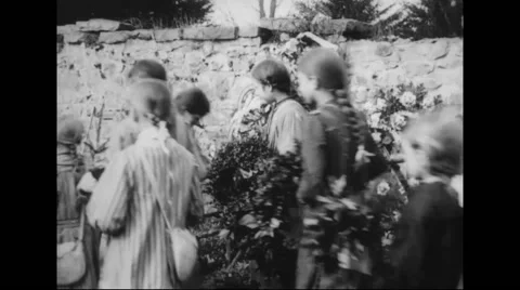 Girls and nuns laying wreath and bouquet in graveyard Stock Footage