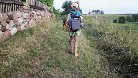 Girls with backpack walking on the rural path with her dog friend. Vídeo Stock 157910979