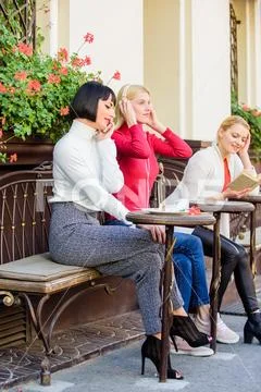 Girls in cafe. social diversity. listening music. reading book. speaking on Stock Photos