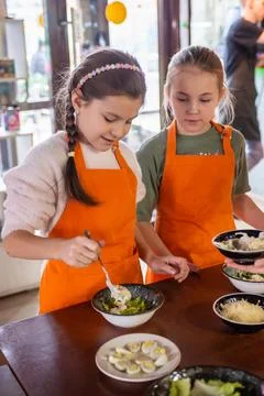 Girls at a culinary workshop on making Caesar salad in a restaurant. Stock Photos