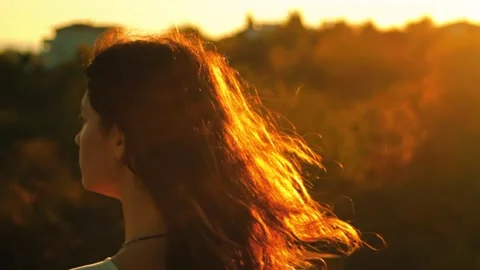 The girls hair is developing in the wind in the light of the setting sun. Video stock 314982739