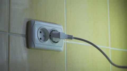 The girl's hand inserts an electric plug into the outlet close-up Video stock 255817872