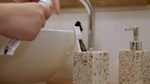 Girl's hand squeezing toothpaste at bathroom sink Stock Footage 283524974