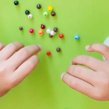 Girl's hand stringing beads on a string. Needlework and craft Stock Photos
