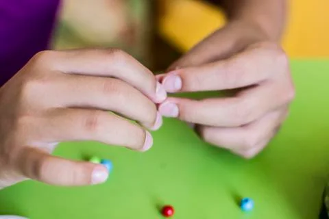 Girl's hand stringing beads on a string. Needlework and craft Stock Photos