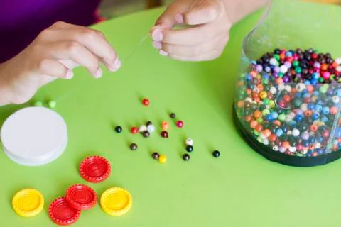 Girl's hand stringing beads on a string. Needlework and craft Stock Photos
