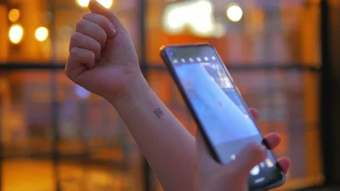 Girl’s hand on which a QR code is applied and a mobile phone with which scan Stockbeeldmateriaal 134634527