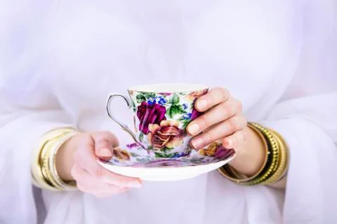 Girl's hands with bracelets  holding a colorful cup Stock Photos