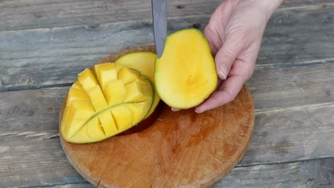 Girl`s hands cuts mango half cut into the cubes on the wooden background Stock Footage 129626042