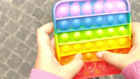 Girl's hands push it modern trendy rainbow silicone toy. New trendy wave Stock Footage 155286499