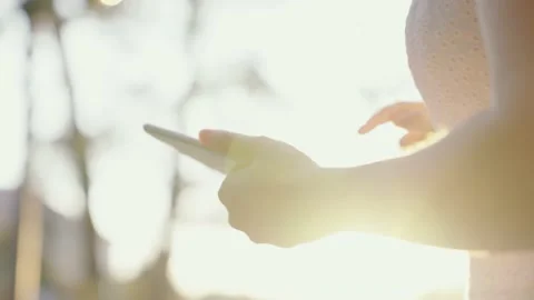 The girl's hands touch touch screen of tablet in rays of sun. Business woman Stockbeeldmateriaal 162281932