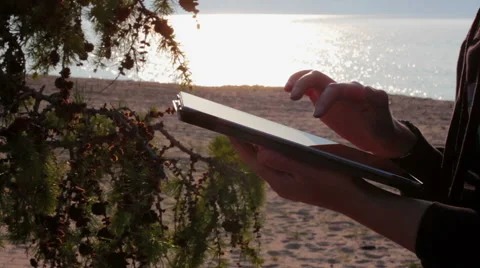 Girl's hands using a tablet pc on the Baikal beach Stock Footage 68105986