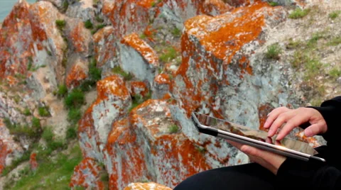 Girl's hands using a tablet PC on the rock, Olkhon Island, Lake Baikal Stock Footage 68150061