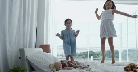 Girls jumping on the bed watching the camera and having fun Stock Footage 100940138